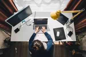 Frau sitzt im Homeoffice beim Schreibtisch und arbeitet am Laptop